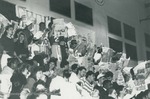 Bridgewater College, Photograph of student sports fans on bleachers, some holding up newspapers, undated by Bridgewater College