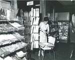 Bridgewater College, Employee arranging card rack at campus store, undated by Bridgewater College