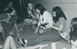 Bridgewater College, Women seated on the floor of a residence hallway share a snack, circa 1973 by Bridgewater College